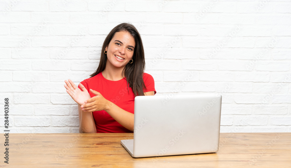Young girl with pc in a table applauding Young girl with pc in a table applauding