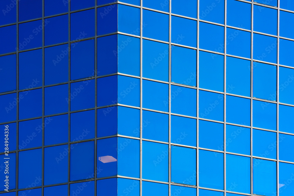 Glass blue square Windows of facade modern city business building skyscraper. Modern apartment buildings in new neighborhood. Windows of a building, texture. Glass blue square Windows of facade modern city business building skyscraper. Modern apartment buildings in new neighborhood. Windows of a building, texture.