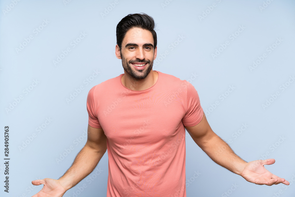 Fototapeta premium Handsome young man in pink shirt over isolated blue background smiling