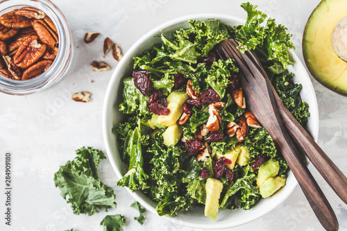 фотографія Green kale salad with cranberries and avocado in white bowl, top view