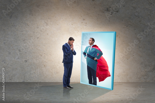 Tableau sur toile Businessman seeing himself in mirror as superhero