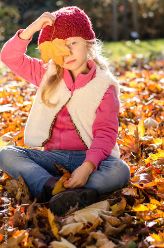 cute kid playing with fallen colorful leaves