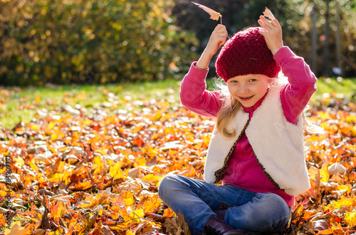 cute kid playing with fallen colorful leaves