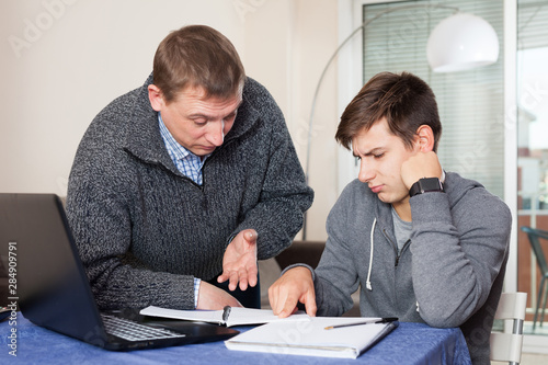 Father checks school assignments teenager son