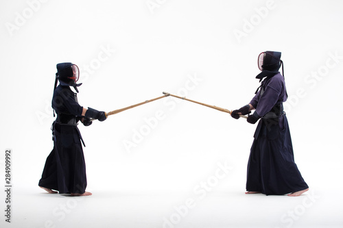 two Kendo martial arts fighters combat fighting in silhouette isolated on white bacground