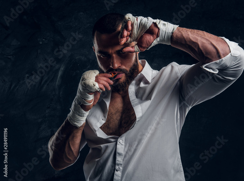 фотографія Handsome brutal man in protective boxing gloves is vering mouth guard while posing for photographer