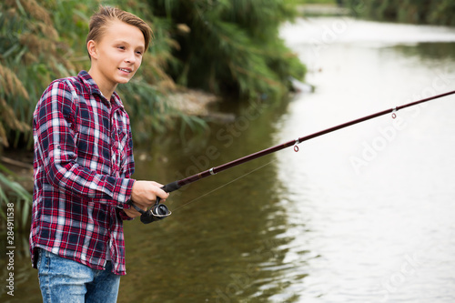 Portrait of glad boy casting line for fishing
