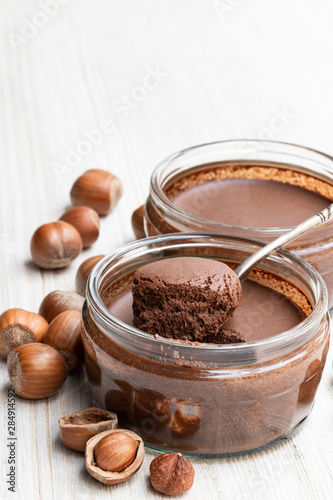 Homemade chocolate hazelnut praline in glass jar on white wooden table