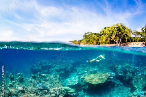 A woman snorkelling over a coral  reef off the coast of Espiritu Santo, Vanuatu.