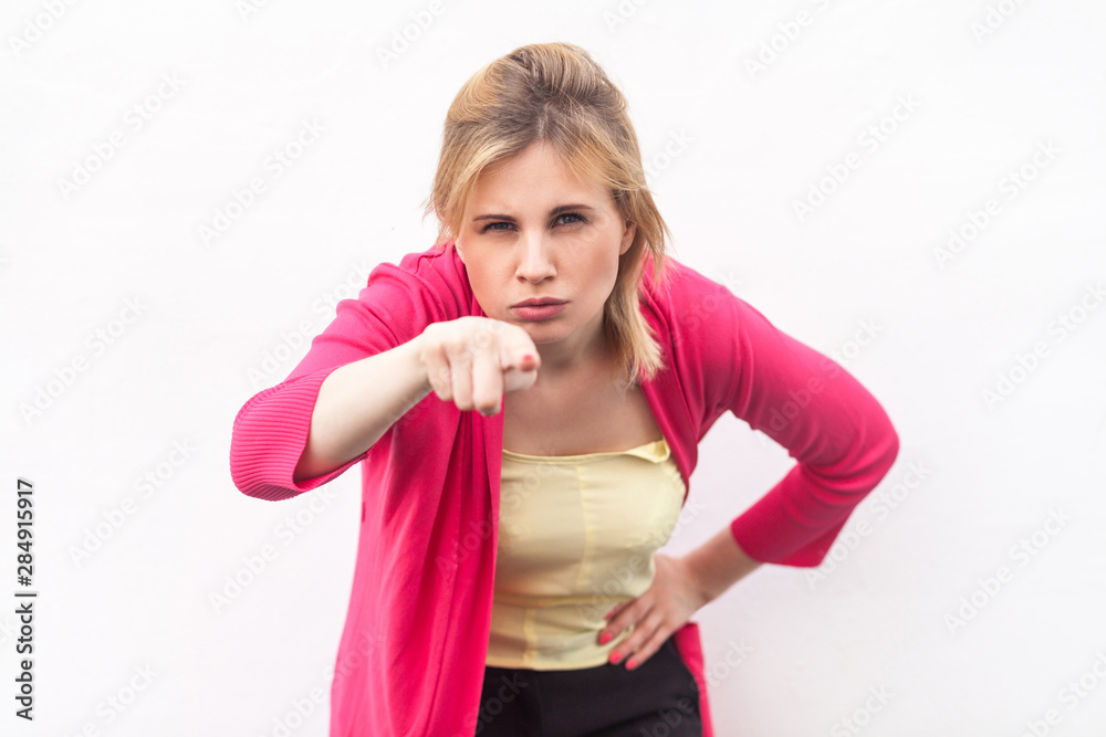 Portrait of serious beautiful blond young woman in yellow shirt and red blouse standing, looking and pointing at camera with serious angry face. indoor studio shot, isolated on white wall background. Portrait of serious beautiful blond young woman in yellow shirt and red blouse standing, looking and pointing at camera with serious angry face. indoor studio shot, isolated on white wall background.