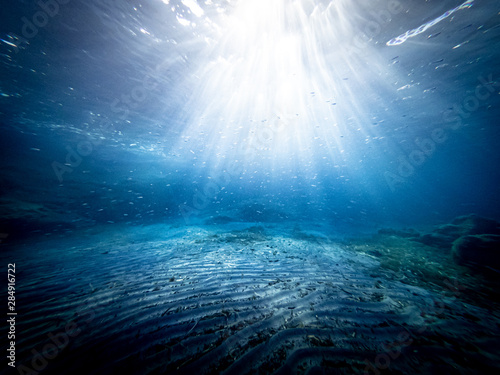 Underwater view of the seabed in San Lorenzo beach, in the southern Sicily, Italy. The shot is takend during a sunny summer day, with rays of light coming inside the water