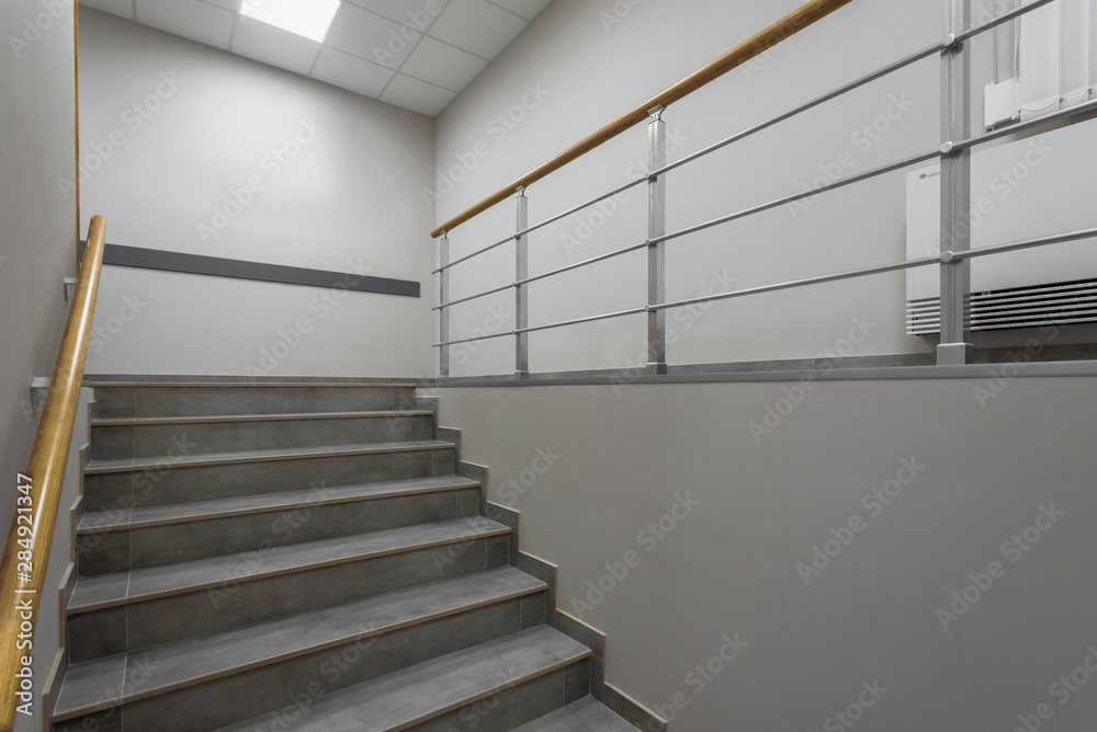 Fototapeta premium Background of gray staircase with wooden handrail in office building