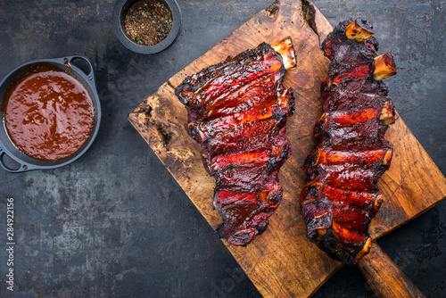 Barbecue chuck beef ribs with hot marinade and chili sauce as top on a wooden cutting board with copy space