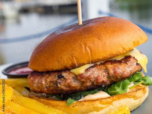 Obraz na płótnie delicious beef burgers with salad trimmings, french fries. Close-up of home made tasty burger with french fries on wooden table. w salonie