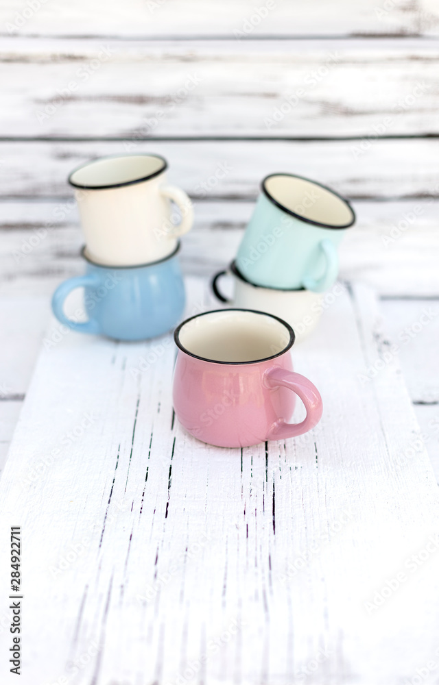 Enameled mugs in retro style on an old wooden background. Enameled mugs in retro style on an old wooden background.