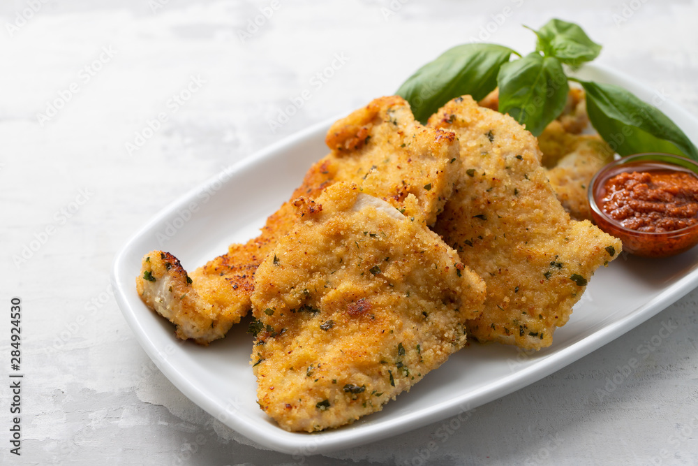 fried chicken breast with sauce on white dish on ceramic background fried chicken breast with sauce on white dish on ceramic background