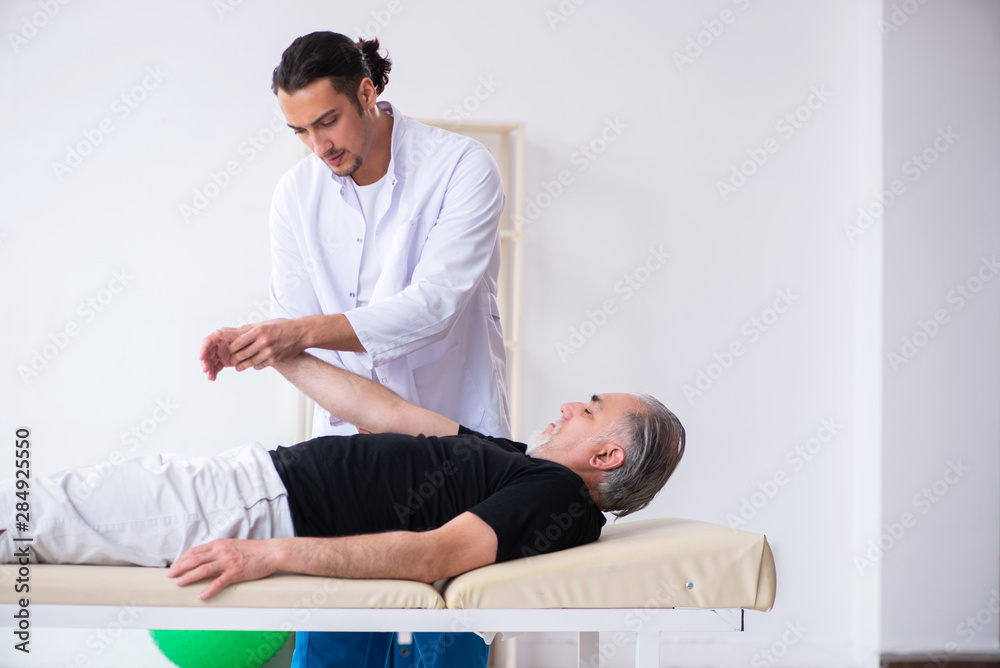 Old injured man visiting young doctor Old injured man visiting young doctor