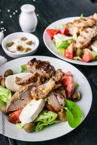 Close-up of grilled meat and salad with vegetables, mozzarella and herbs. Traditional Mediterranean Cuisine