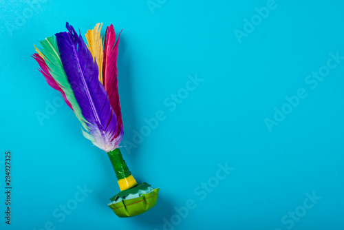 Shuttlecock with colorful feathers on neon blue background. Space for text on the right side of the image.