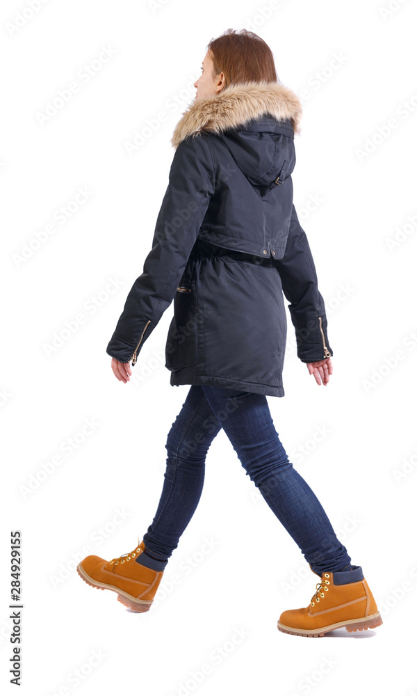 Naklejka premium Back view of going woman in jeans and winter jacket.