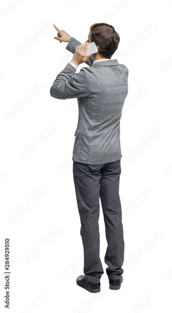 Obraz premium back view of pointing business man in suit talking on mobile phone.