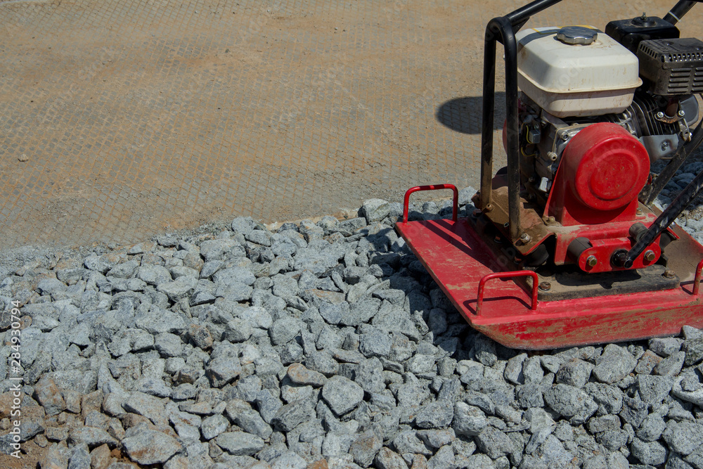 Rammer at work. Rammer rubble on the edge of the road. Construction work on the road Rammer at work. Rammer rubble on the edge of the road. Construction work on the road