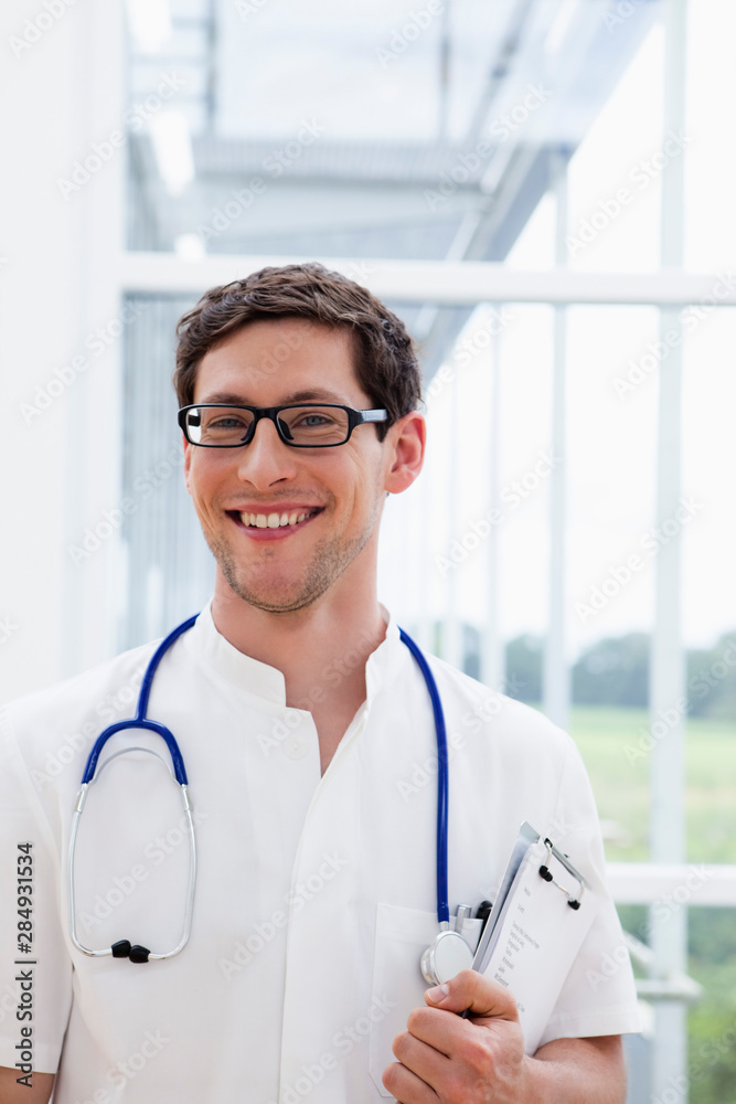 Germany, Bavaria, Diessen am Ammersee, Close up of young doctor with stethoscope, smiling, portrait Germany, Bavaria, Diessen am Ammersee, Close up of young doctor with stethoscope, smiling, portrait