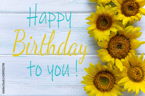 Happy Birthday. Greeting card with flowers for a girl, mom's birthday. View from above. Sunflower flowers on a light wooden background
