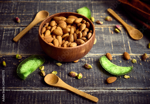 Almonds in a bowl against dark rustic wooden background photo