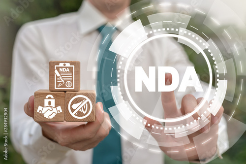 NDA Non-Disclosure Agreement Business concept. Man holding wooden cubes with confidentiality icons and pushing nda acronym virtual button. photo