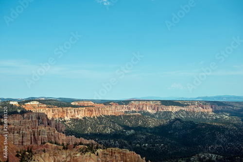 Wide view over valley at Bryce Canyon with mountains full of trees