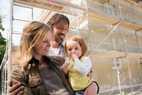Young family in front of New Home Under Construction photo