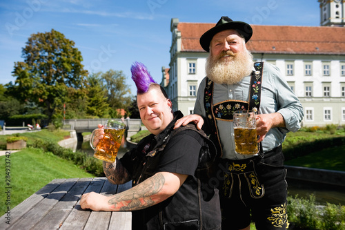 Germany, Bavaria, Upper Bavaria, Man with mohawk hairstyle and Bavarian man in beer garden