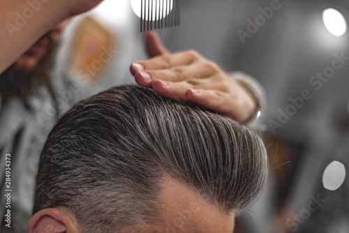 Fototapeta Barber does hair styling. Men's Hair Care.