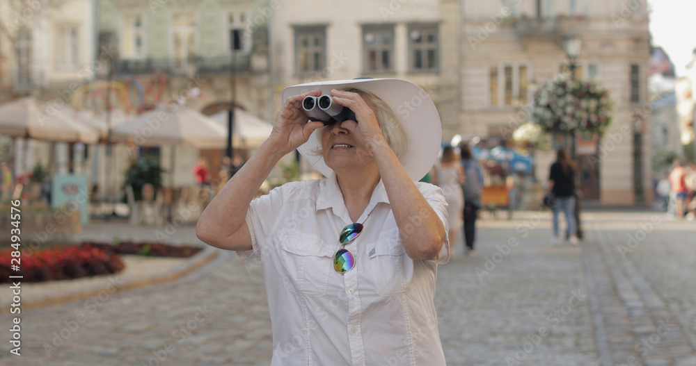 Senior woman tourist exploring town. Looking in binoculars. Travel Lviv, Ukraine