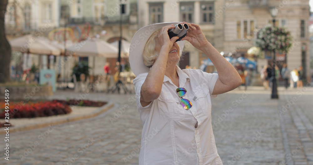 Senior woman tourist exploring town. Looking in binoculars. Travel Lviv, Ukraine