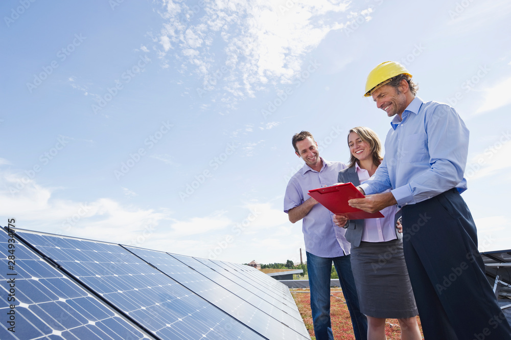 Germany, Munich, Engineer with man and woman in solar plant, smiling Germany, Munich, Engineer with man and woman in solar plant, smiling