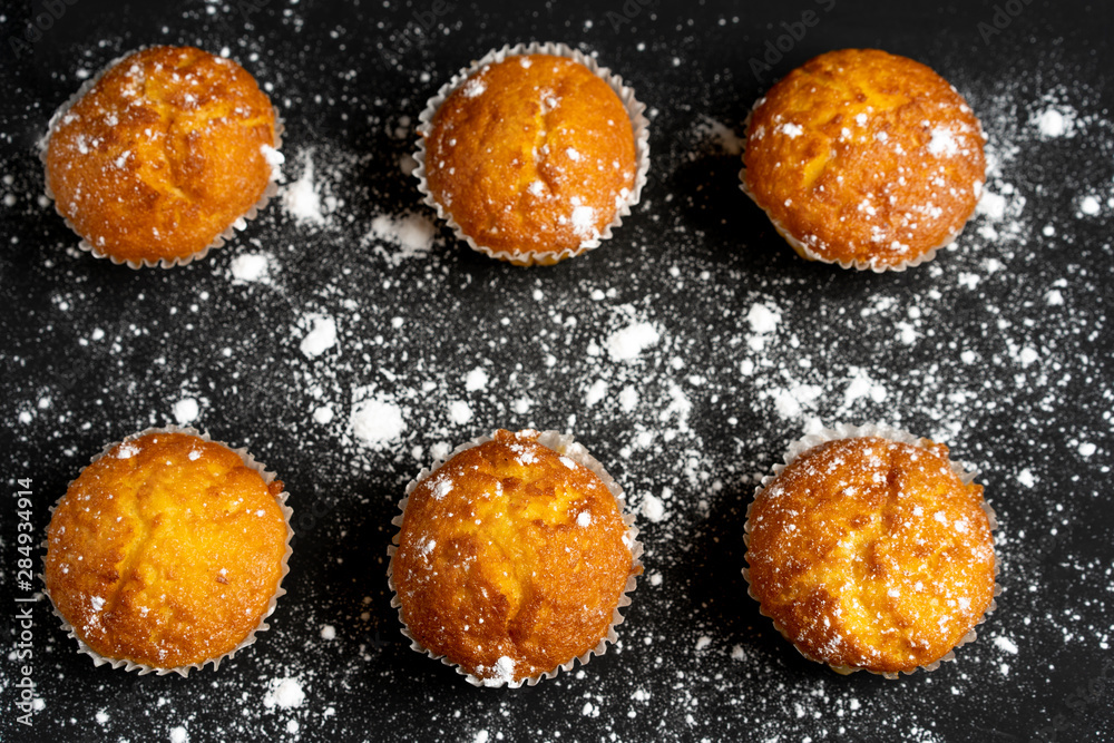 Appetizing muffins stand on a table top view. Traditional pastries on a dark background minimalism. Appetizing muffins stand on a table top view. Traditional pastries on a dark background minimalism.