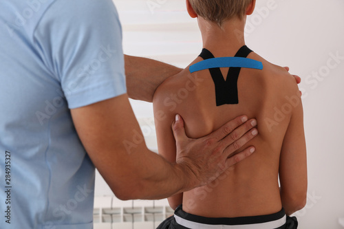 Boy having chiropractic back adjustment. Osteopathy, Physiotherapy and Kinesiology for children. Bad posture correction