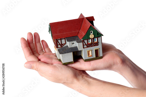 Plastic model of an old house in female hands on a white background