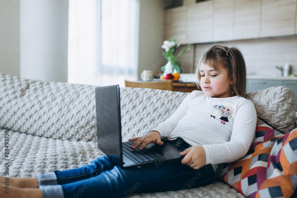Girl sitting on sofa with laptop in scandinavian room interior, technology, new generation, scandinavian home concept