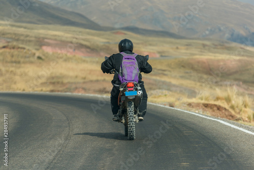 A motorbiker drives through the Peruvian Highlands, Peru