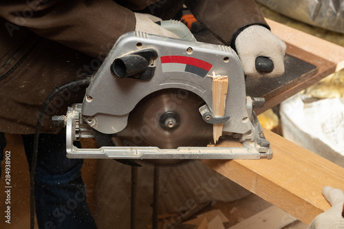 Man works as a carpenter with circular saw in his workshop