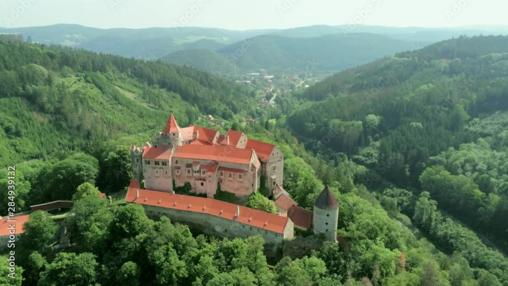 Aerial View of Fabulous Medieval Pernstejn Castle (hrad Pernstejn) in Mountain Forest in Czech Republic, Europe on Sunny Summer Day with Town and River at Background. 4K Bird's-eye view Zoom Shot Aerial View of Fabulous Medieval Pernstejn Castle (hrad Pernstejn) in Mountain Forest in Czech Republic, Europe on Sunny Summer Day with Town and River at Background. 4K Bird's-eye view Zoom Shot