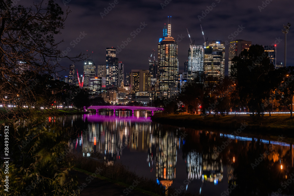 Melbourne Skyline at night with magenta lit bridge in foreground