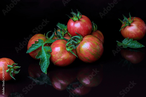 Colorful fresh striped tomatoes. Organic farm product, black background. Texture, close-up.