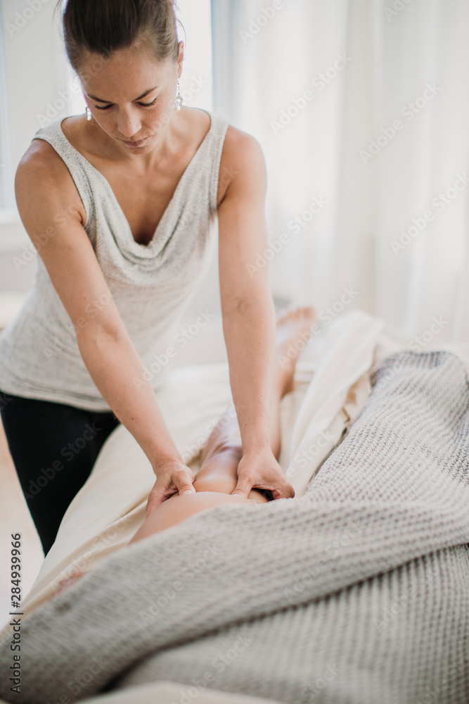 A female massage therapist treats the quadricep of one of her clients A female massage therapist treats the quadricep of one of her clients