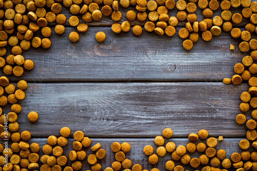 Cat dry food frame on wooden background top view copyspace