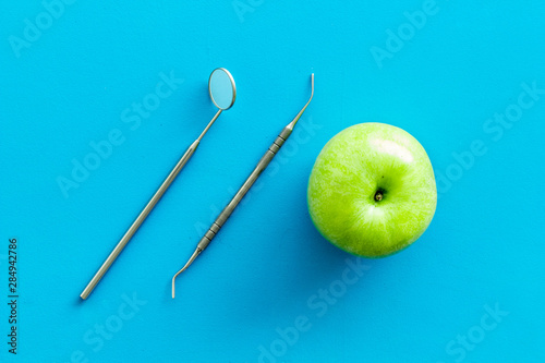 stomatologist mirror and apple on blue doctor's office desk background top view photo