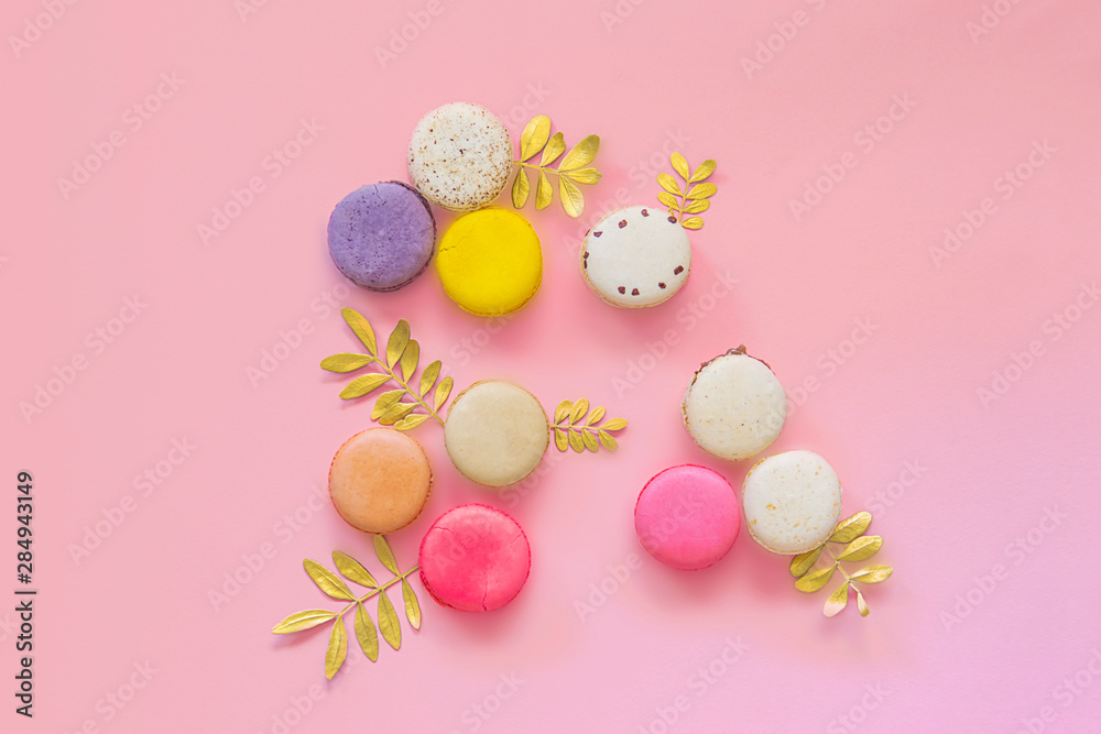 French colorful macaroons cakes flat lay. Small sweet biscuits isolated on pink background. Dessert. Happy bithday and valentine’s day creative minimal concept.  Confectionery. Bakery design element.